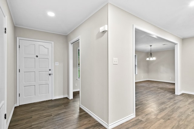 entrance foyer featuring an inviting chandelier, crown molding, and dark hardwood / wood-style flooring