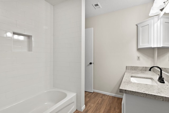 bathroom featuring vanity, hardwood / wood-style floors, a textured ceiling, and shower / bathing tub combination