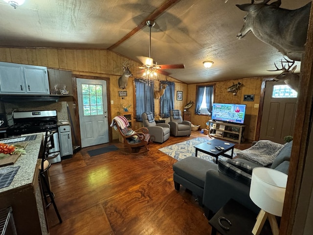 living room with ceiling fan, dark hardwood / wood-style flooring, lofted ceiling, and wooden walls