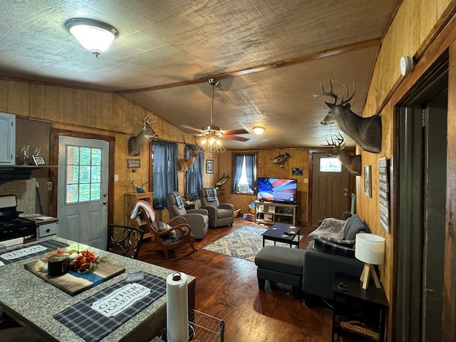 living room featuring wood walls, ceiling fan, wood-type flooring, and lofted ceiling