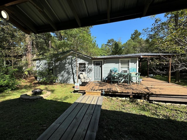 rear view of house featuring a lawn, a fire pit, and a deck