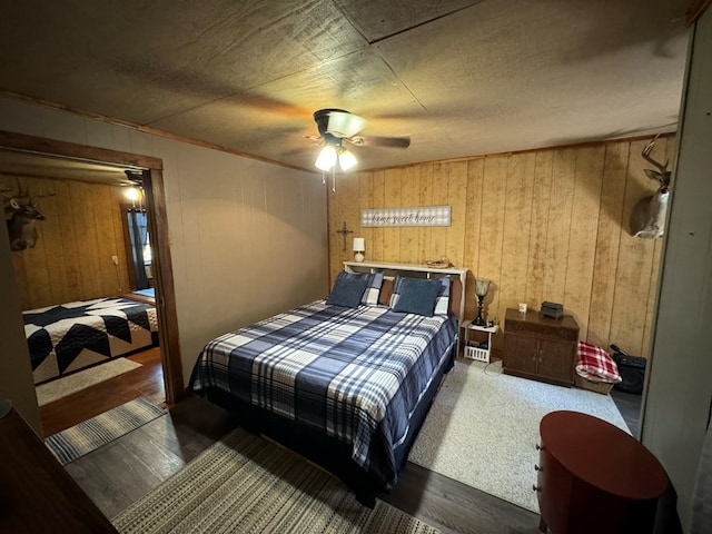 bedroom featuring wood walls, ceiling fan, and dark hardwood / wood-style floors