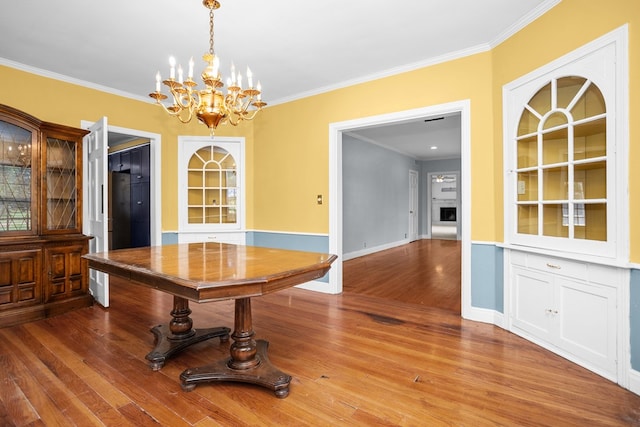 715 Pine Tree Ln, Lufkin, TX 75904 - unfurnished dining area with built in shelves, a chandelier, ornamental molding, wood finished floors, and baseboards