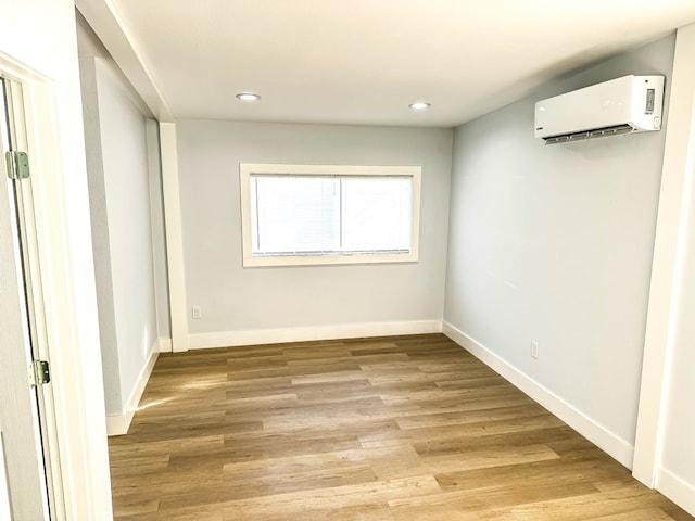 spare room featuring an AC wall unit and light hardwood / wood-style flooring