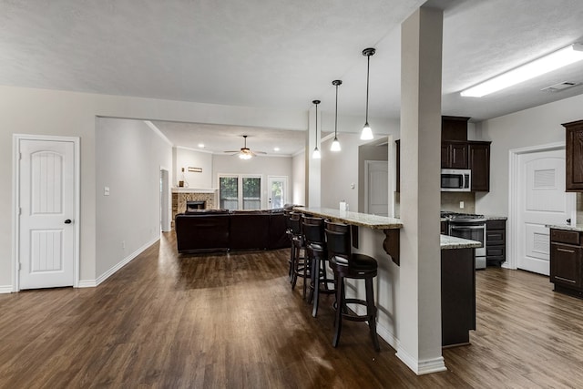 801 Dove Run Trl, College Station, TX 77845 - kitchen featuring appliances with stainless steel finishes, dark wood-style floors, a breakfast bar area, and a ceiling fan
