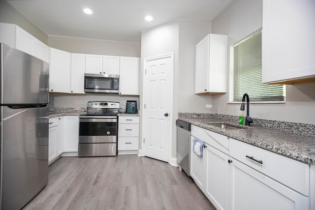 206 Shady Pnes, Lufkin, TX 75901 - kitchen featuring appliances with stainless steel finishes, a sink, light wood-type flooring, white cabinets, and light stone counters