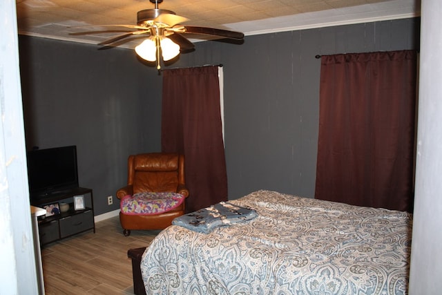 bedroom with crown molding, wood-type flooring, and ceiling fan