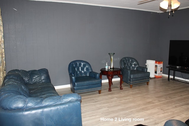 living room featuring crown molding, radiator, ceiling fan, and light wood-type flooring