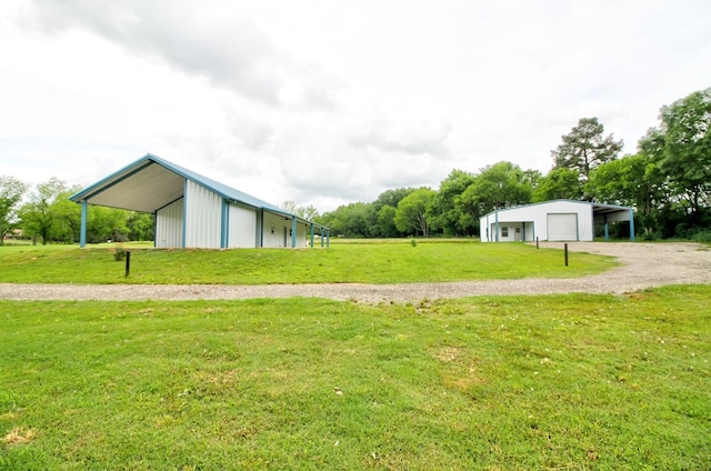 view of yard with a pole building, an outbuilding, driveway, and a detached garage