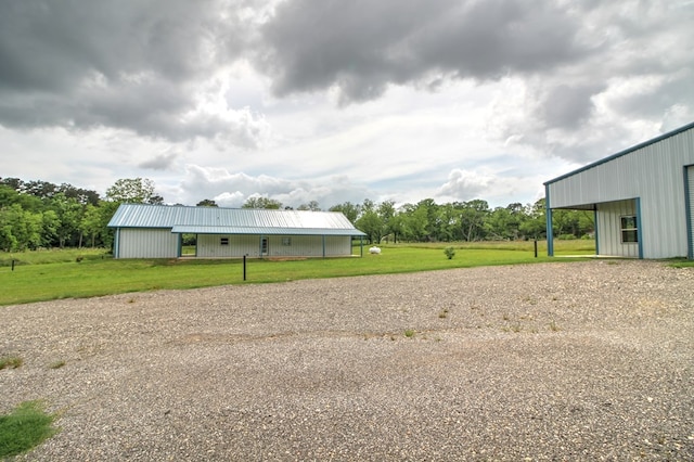 view of yard with a pole building, an outbuilding, and gravel driveway