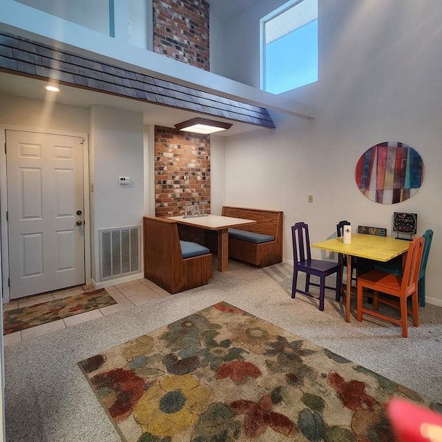 dining area featuring a towering ceiling and light colored carpet