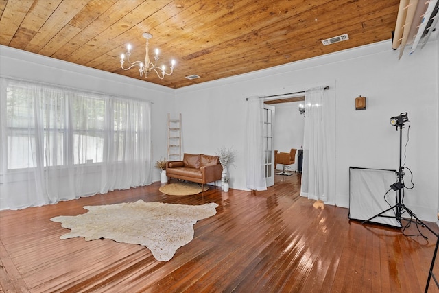 living area with wood-type flooring, ornamental molding, a notable chandelier, and wood ceiling