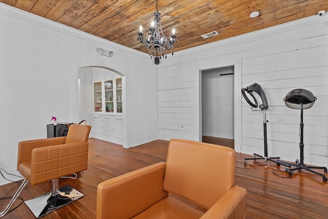 sitting room with wood-type flooring, an inviting chandelier, crown molding, and wood ceiling