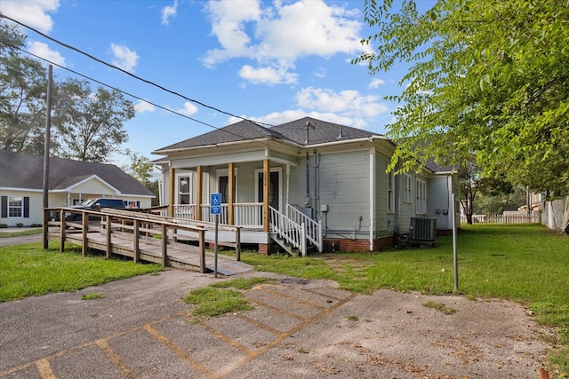 view of front of property featuring a front lawn, central AC unit, and a porch