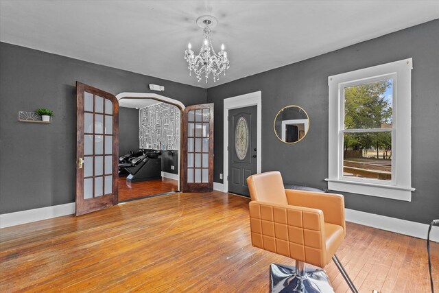 sitting room with hardwood / wood-style floors, french doors, and an inviting chandelier