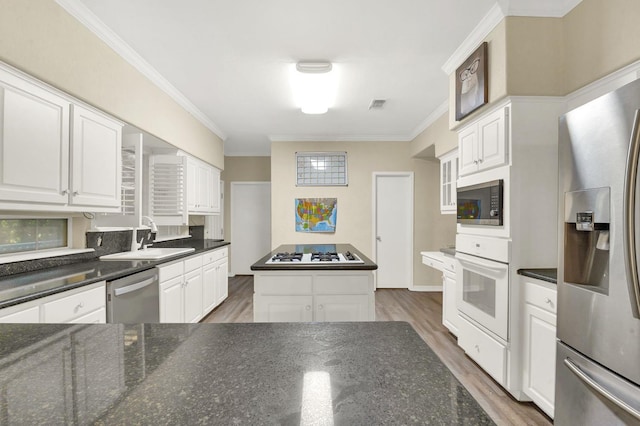 kitchen with sink, dark hardwood / wood-style flooring, appliances with stainless steel finishes, white cabinets, and ornamental molding