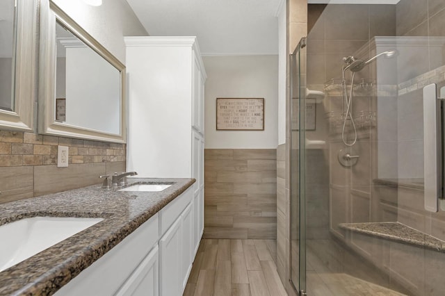 bathroom featuring wood-type flooring, vanity, a shower with door, and tile walls