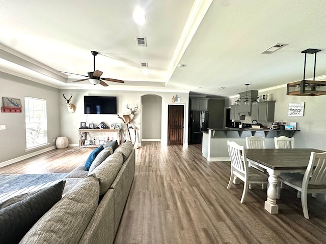 3640 Wingate Blvd, Brookeland, TX 75931 - living room with dark wood-style floors, a ceiling fan, arched walkways, a tray ceiling, and crown molding