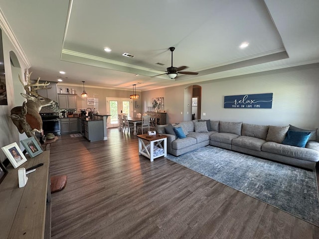 3640 Wingate Blvd, Brookeland, TX 75931 - living area featuring a tray ceiling, arched walkways, dark wood finished floors, crown molding, and a ceiling fan