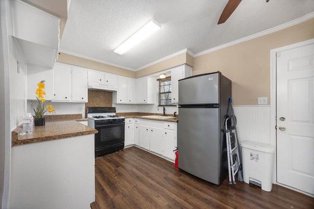 kitchen featuring dark wood-style flooring, under cabinet range hood, a sink, gas range, and freestanding refrigerator