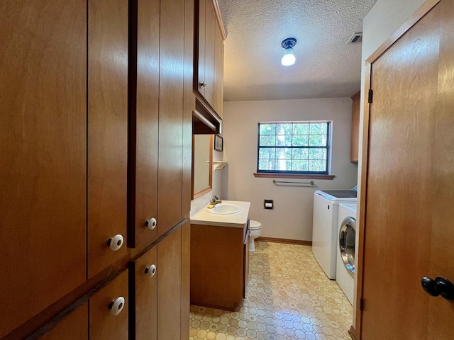 laundry area with a textured ceiling, sink, and independent washer and dryer