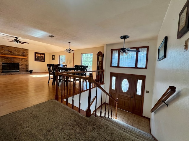 entrance foyer featuring a textured ceiling, hardwood / wood-style floors, ceiling fan with notable chandelier, and a fireplace