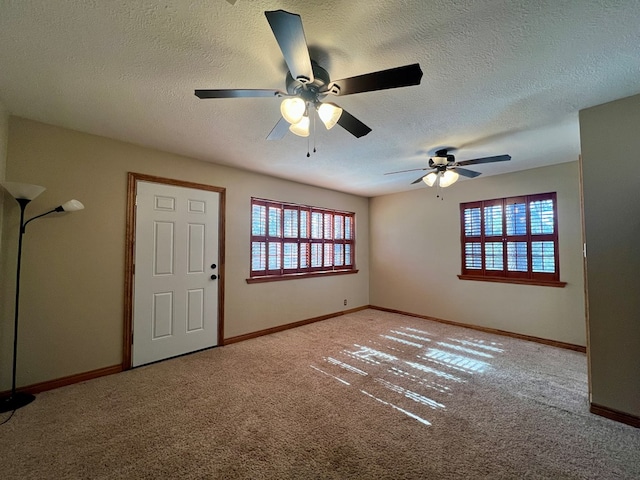 spare room featuring ceiling fan, light carpet, and a textured ceiling