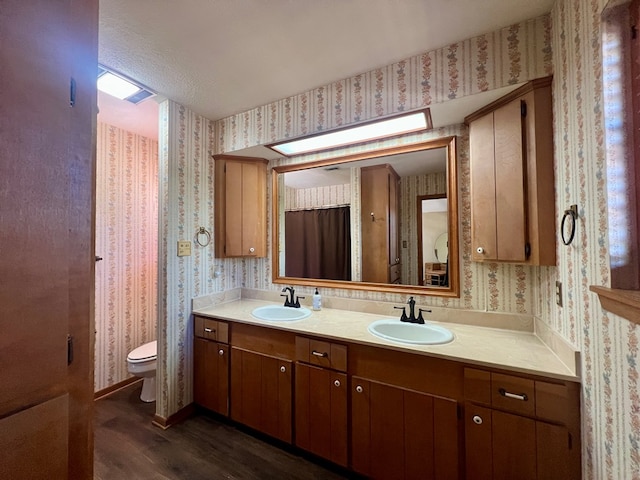 bathroom featuring toilet, vanity, a textured ceiling, and hardwood / wood-style flooring