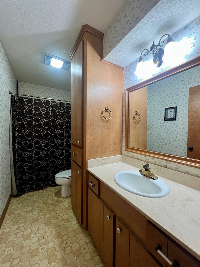 bathroom featuring a textured ceiling, walk in shower, vanity, and toilet