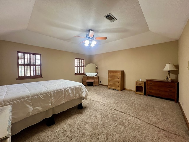 bedroom with a raised ceiling, carpet floors, and ceiling fan