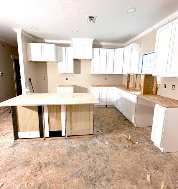 kitchen with crown molding, a kitchen island, and white cabinets