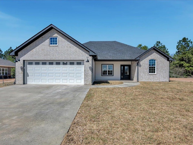 view of front facade featuring a front lawn, a garage, driveway, and a shingled roof