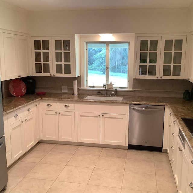 kitchen with dishwasher, sink, decorative backsplash, dark stone countertops, and white cabinetry