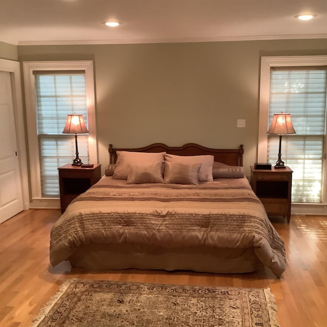 bedroom featuring ornamental molding and light hardwood / wood-style flooring