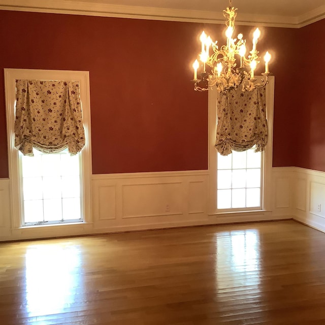 empty room featuring an inviting chandelier, crown molding, and light hardwood / wood-style flooring