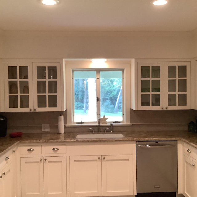 kitchen with light stone counters, sink, white cabinets, and stainless steel dishwasher