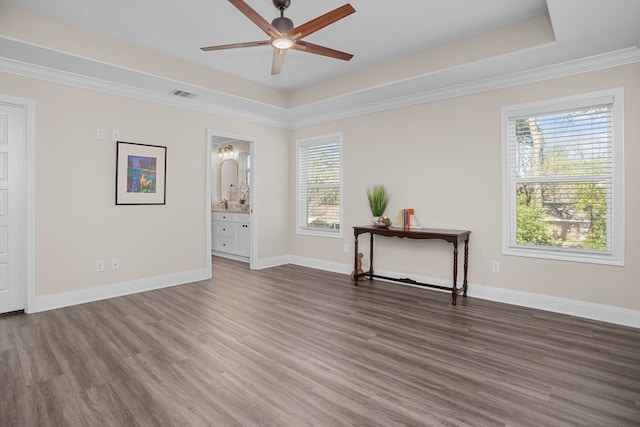 unfurnished room featuring baseboards, visible vents, ceiling fan, dark wood-style flooring, and a tray ceiling
