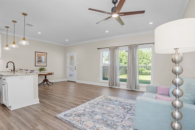 living area with light wood finished floors, recessed lighting, visible vents, ornamental molding, and baseboards