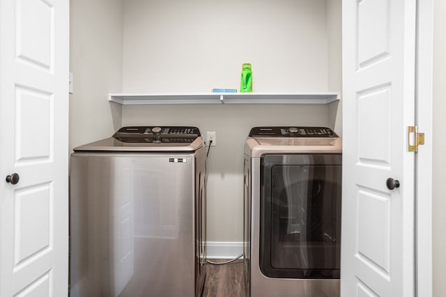 laundry area with laundry area, dark wood-style flooring, washing machine and clothes dryer, and baseboards