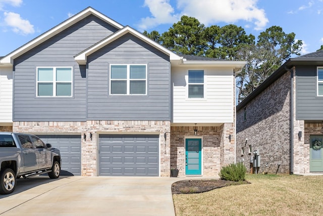 view of property featuring a garage, driveway, brick siding, and a front lawn