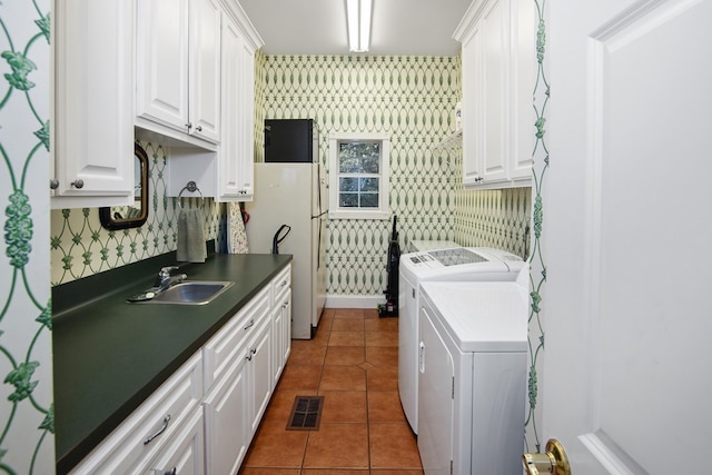 kitchen featuring white cabinets, washer and clothes dryer, sink, and dark tile patterned flooring