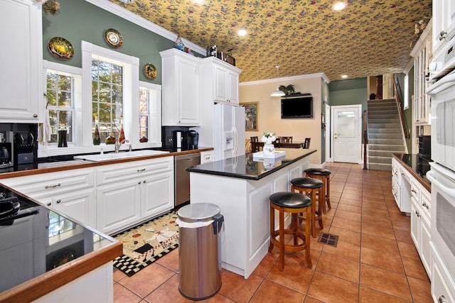 kitchen featuring brick ceiling, white appliances, white cabinetry, and a center island