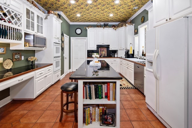 kitchen featuring tile patterned flooring, crown molding, stainless steel appliances, and white cabinetry