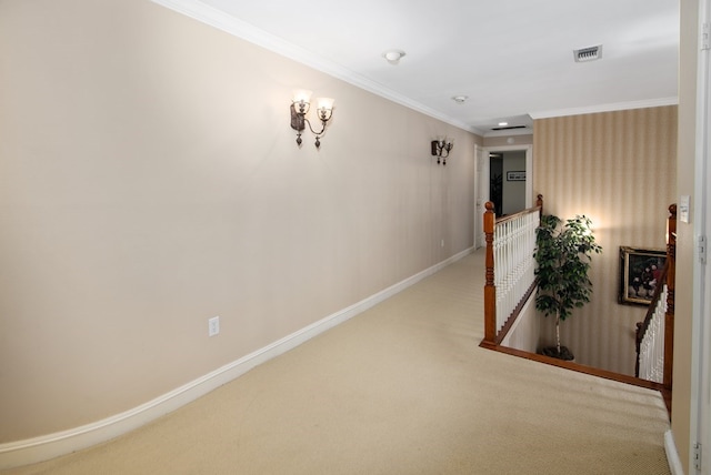 hallway with carpet floors, visible vents, ornamental molding, an upstairs landing, and baseboards