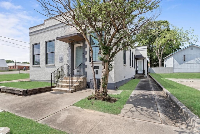 shotgun-style home with brick siding, fence, and a front yard