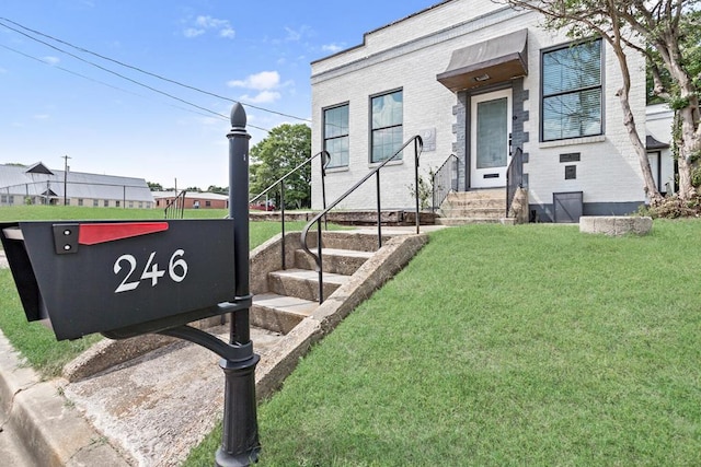 view of front of property featuring brick siding, a front yard, and entry steps