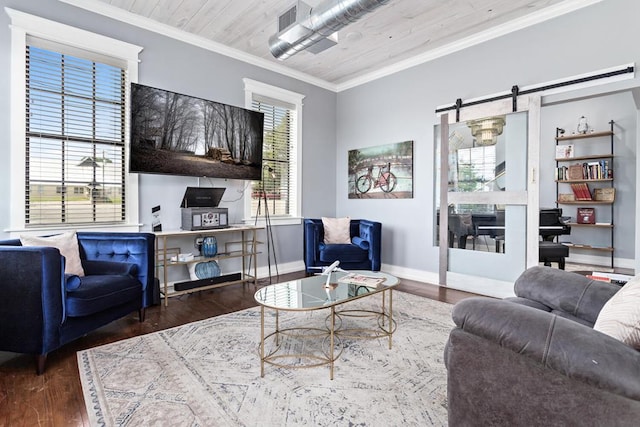 living area with a barn door, baseboards, ornamental molding, and wood finished floors