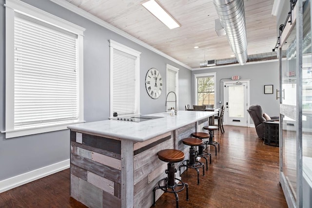 kitchen featuring visible vents, baseboards, an island with sink, black electric cooktop, and dark wood finished floors