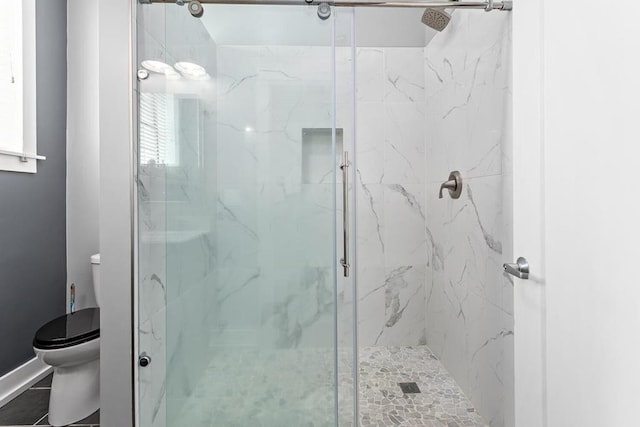 bathroom featuring a stall shower and toilet