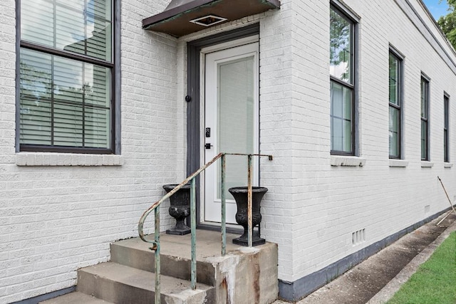 property entrance featuring brick siding and crawl space